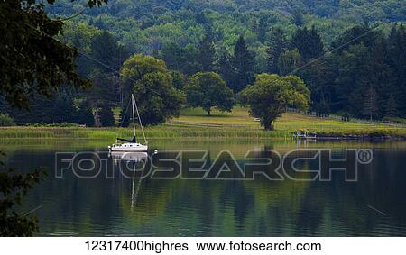Sailboat at dusk on a lake with the mirror image reflected in the water; Knowlton, Quebec, Canada View Large Photo Image Stock Photograph - Sailboat at dusk on a lake with the mirror image reflected in the water; Knowlton, Quebec, Canada. Fotosearch