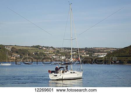 Stock Image - Sailboat in a harbour with buildings on the shore; Kinsale, County Cork, Ireland. Fotosearch