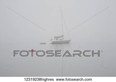 Stock Photograph - Sailboat moored in the fog; Magog, Quebec, Canada. Fotosearch