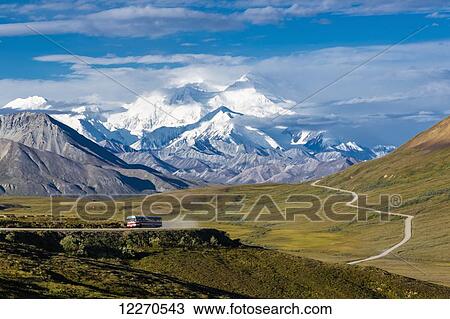 Stock Image - Scenic view of Mt. McKinley and Thorofare Pass with a tourist lodge bus in the foreground in Denali National Park, Interior Alaska, Summer, USA. Fotosearch