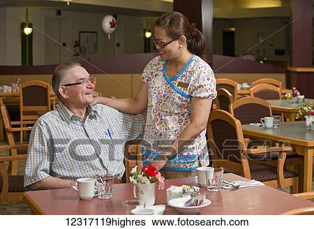 Senior citizen and caregiver in cafeteria; Devon, Alberta, Canada View Large Photo Image Stock Photograph - Senior citizen and caregiver in cafeteria; Devon, Alberta, Canada. Fotosearch