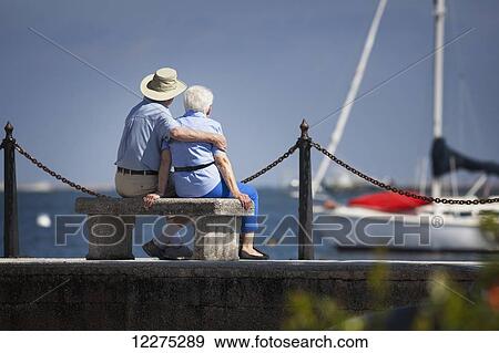 Senior couple sitting on a park bench looking out over the bay with sailboats at anchor; St. Augustine, Florida, United States of America View Large Photo Image Stock Photo - Senior couple sitting on a park bench looking out over the bay with sailboats at anchor; St. Augustine, Florida, United States of America. Fotosearch