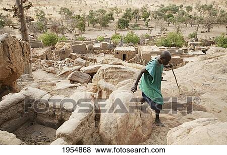 Stock Photo - Senior man walking by the Toguna (House of words) in Tireli, Mali. Fotosearch