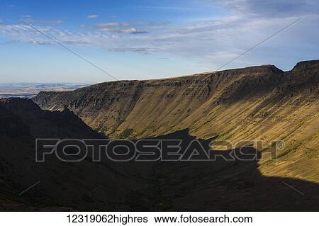 Stock Photograph - Shadow fills Kiger Gorge at Steens Mountain; Frenchglen, Oregon, United States of America. Fotosearch