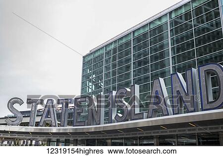 Stock Photograph - Sign for Staten Island at the ferry terminal with a glass facade building in the background; New York City, New York, United States of America. Fotosearch