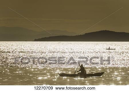 Stock Photo - Silhouette of fisherman off Cape Maclear in the evening, Lake Malawi; Malawi. Fotosearch