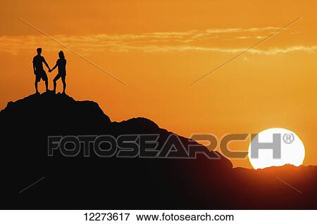 Silhouetted couple holding hands on a big rock at sunset; Oahu, Hawaii, United States of America View Large Photo Image Stock Photo - Silhouetted couple holding hands on a big rock at sunset; Oahu, Hawaii, United States of America. Fotosearch