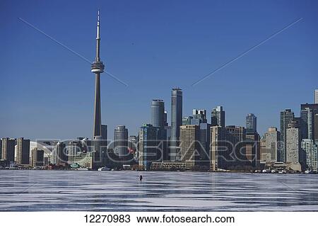 Stock Image - Skater against city skyline in winter; Toronto, Ontario, Canada. Fotosearch