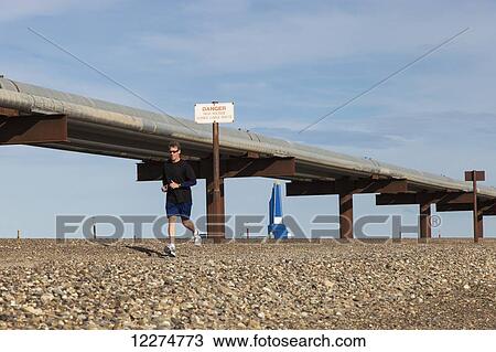 Slope worker running in the Endicott Fun Run with oil pipelines and the Liberty Oil Rig in the background, Prudhoe Bay Oil field, North Slope, Arctic Alaska, Summer View Large Photo Image Stock Image - Slope worker running in the Endicott Fun Run with oil pipelines and the Liberty Oil Rig in the background, Prudhoe Bay Oil field, North Slope, Arctic Alaska, Summer. Fotosearch