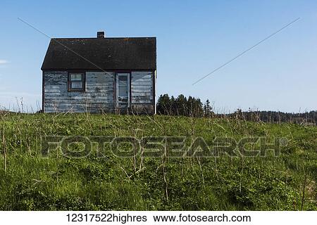 Stock Photograph - Small weathered wooden house surrounded by grass on Cape Breton Island; Nova Scotia, Canada. Fotosearch