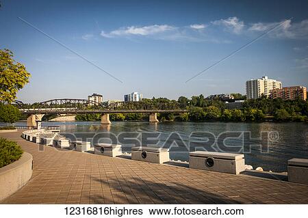 Stock Photograph - South Saskatchewan River with bridge and promenade; Saskatoon, Saskatchewan, Canada. Fotosearch