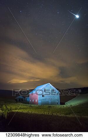 Stock Photograph - Stars and constellations above a farmhouse and barn in a wheat field at night; Palouse, Washington, United States of America. Fotosearch