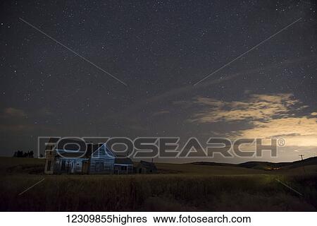 Stock Photograph - Stars glowing in the sky at dusk over a farmhouse; Palouse, Washington, United States of America. Fotosearch