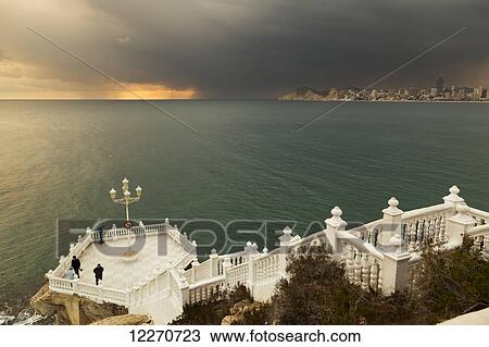 Storm clouds at sunset and a white railing leading down steps to a platform on the waterfront; Benidorm, Spain View Large Photo Image Stock Image - Storm clouds at sunset and a white railing leading down steps to a platform on the waterfront; Benidorm, Spain. Fotosearch