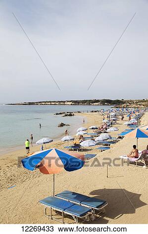 Stock Image - Sunbathing on the beach along the mediterranean; Peyia, Paphos, Cyprus. Fotosearch
