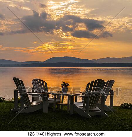 Stock Photograph - Sunset on lake with silhouetted chairs on wharf; Knowlton, Quebec, Canada. Fotosearch