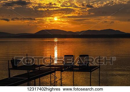 Sunset on lake with silhouetted chairs on wharf; Knowlton, Quebec, Canada View Large Photo Image Stock Photograph - Sunset on lake with silhouetted chairs on wharf; Knowlton, Quebec, Canada. Fotosearch