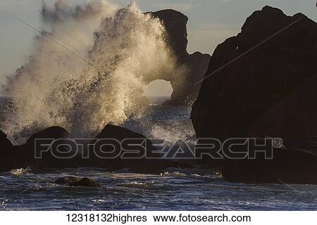 Stock Photograph - Surf breaks on the rocks near a natural arch at Ecola State Park; Cannon Beach, Oregon, United States of America. Fotosearch
