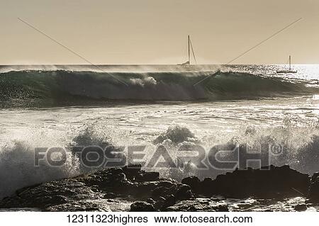 Stock Photograph - Surf on the Kona coast with sailboats on the horizon; Kona, Island of Hawaii, Hawaii, United States of America. Fotosearch