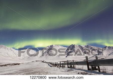 Stock Image - The Aurora Borealis (Northern Lights) dancing over the Trans Alaska Oil Pipeline on the south side of Atigun Pass in the Brooks Range, Arctic Alaska, Winter. Fotosearch