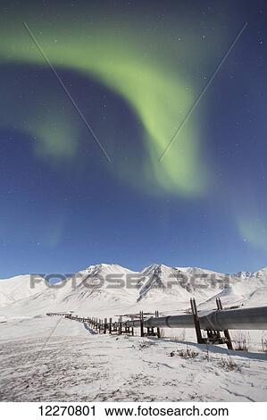 Stock Image - The Aurora Borealis (Northern Lights) dancing over the Trans Alaska Oil Pipeline on the south side of Atigun Pass in the Brooks Range, Arctic Alaska, Winter. Fotosearch