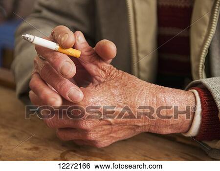 Stock Photograph - The hands of a senior man holding a cigarette and smoking; Xiamen, Fujian province, China. Fotosearch