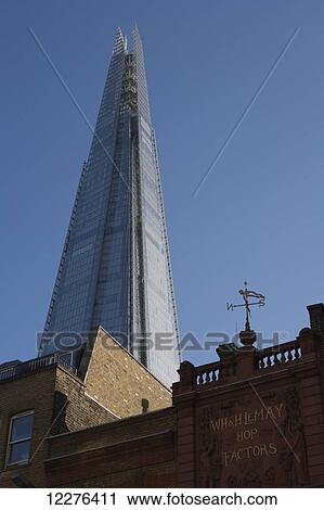 Stock Image - The Shard skyscraper by Renzo Piano rising above a historic building on Borough High Street; London, England. Fotosearch