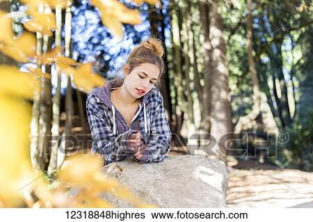 This young teenage girl hangs out alone in a park, sitting on a rock in a thoughtful disengaged position thinking to herself; New Westminster, British Columbia, Canada View Large Photo Image Stock Photograph - This young teenage girl hangs out alone in a park, sitting on a rock in a thoughtful disengaged position thinking to herself; New Westminster, British Columbia, Canada. Fotosearch
