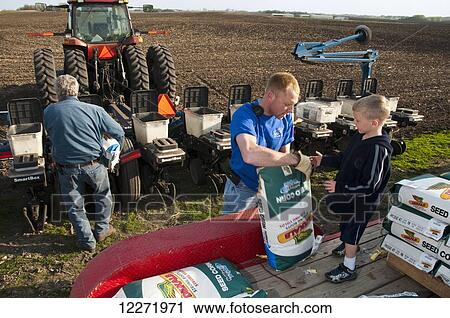 Stock Image - Three generations of family farmers loading their planter with corn seed in preparation for spring planting, near Northrop; Minnesota, United States of America. Fotosearch