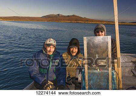 Picture - Three native Alaskan men of the Noatak Search and Rescue sit on a boat on the Noatak River, Noatak Arctic Alaska, USA, Fall. Fotosearch