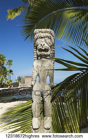 Stock Photograph - Tiki carving in Pu'u Honua O Honaunau National Park in Hawaii with heiau in background; Honaunau, Island of Hawaii, Hawaii, United States of America. Fotosearch
