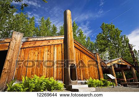 Picture - Tlingit clan house and totem pole at the Haida and Tsimshian Village Site at Alaska Native Heritage Center, Anchorage, Southcentral Alaska, Summer.. Fotosearch