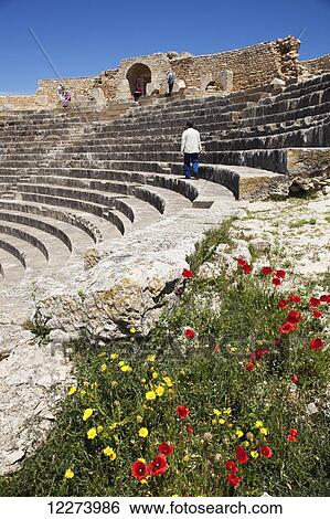 Stock Photograph - Tourist walks through the Roman theatre; Dougga, Tunisia. Fotosearch