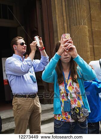 Stock Photo - Tourists on the streets of Florence capture photos with their smart phones; Florence, Italy. Fotosearch