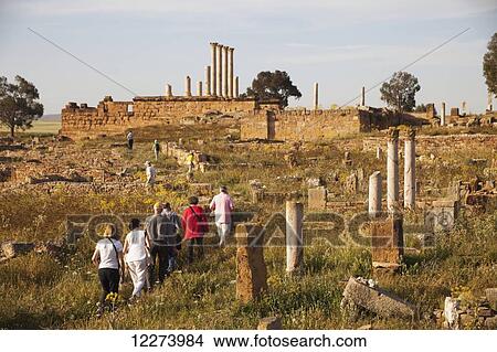 Picture - Tourists walking amongst the ruins towards the Capitoline Temple; Thuburbo Majus, Tunisia. Fotosearch