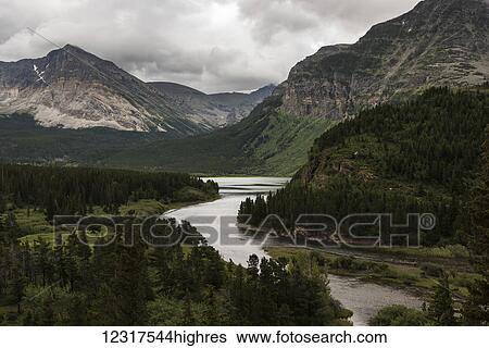 Stock Photograph - Tranquil river flowing through rugged mountains in Glacier National Park; Browning, Montana, United States of America. Fotosearch