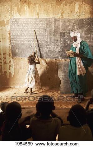 Stock Photo - Tuareg teacher and girl in front of a blackboard at a primary school in Tiriken, Mali. Fotosearch