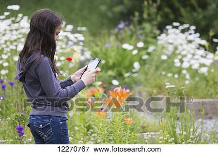 Tween Inipiat eskimo girl holding a smart tablet and taking photos at the Knik Goose Bay Museum in Wasilla, Southcentral Alaska, summer View Large Photo Image Stock Photo - Tween Inipiat eskimo girl holding a smart tablet and taking photos at the Knik Goose Bay Museum in Wasilla, Southcentral Alaska, summer. Fotosearch