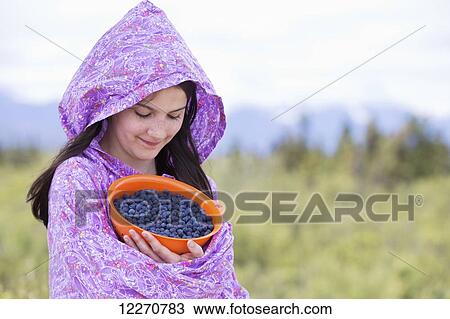 Stock Image - Tween Inupiat eskimo girl in traditional native kuspuk dress holding blueberries, near Glennallen, Southcentral Alaska, Summer. Fotosearch