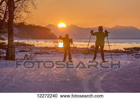 Two back lit people cross country skiing on the Tony Knowles Coastal Trail at sunset, Southcentral Alaska View Large Photo Image Stock Image - Two back lit people cross country skiing on the Tony Knowles Coastal Trail at sunset, Southcentral Alaska. Fotosearch