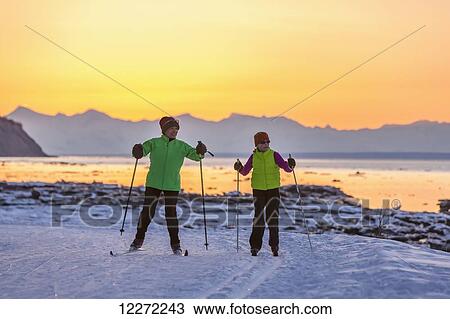 Two back lit people cross country skiing on the Tony Knowles Coastal Trail at sunset, Southcentral Alaska View Large Photo Image Stock Image - Two back lit people cross country skiing on the Tony Knowles Coastal Trail at sunset, Southcentral Alaska. Fotosearch