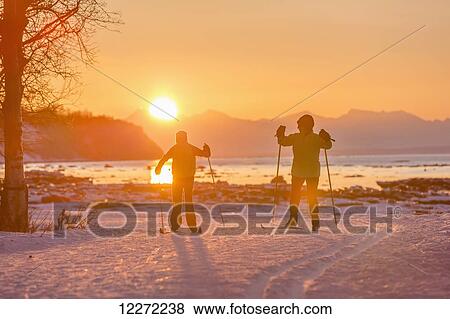 Two back lit people cross country skiing on the Tony Knowles Coastal Trail at sunset, Southcentral Alaska View Large Photo Image Stock Photo - Two back lit people cross country skiing on the Tony Knowles Coastal Trail at sunset, Southcentral Alaska. Fotosearch