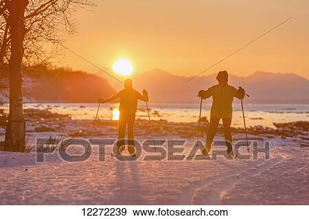 Two back lit people cross country skiing on the Tony Knowles Coastal Trail at sunset, Southcentral Alaska View Large Photo Image Stock Photo - Two back lit people cross country skiing on the Tony Knowles Coastal Trail at sunset, Southcentral Alaska. Fotosearch
