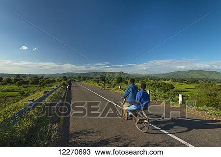 Two boys on bicycle going along road in the late afternoon near Chikwawa; Malawi View Large Photo Image Stock Image - Two boys on bicycle going along road in the late afternoon near Chikwawa; Malawi. Fotosearch