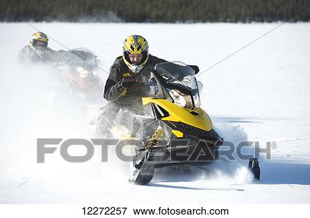 Stock Photo - Two friends snowmachine through fresh snow on Little Harding Lake in Harding Lake State Recreation Area 45 miles south of Fairbanks in Interior Alaska.. Fotosearch