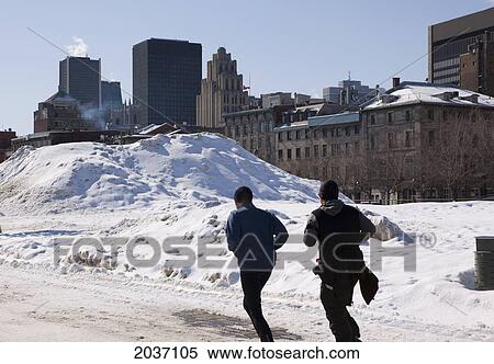 Stock Photography - Two Men Jogging Away In Montreal's Old Port With City In The Background, Wintertime, Montreal, Quebec. Fotosearch