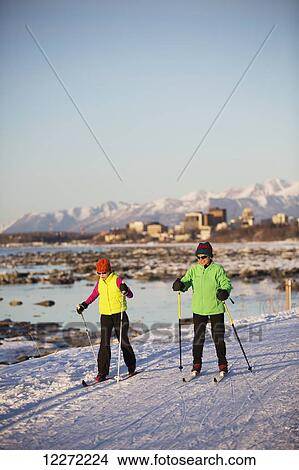 Two people cross country skiing on the Tony Knowles Coastal Trail with Anchorage in the background, Southcentral Alaska View Large Photo Image Picture - Two people cross country skiing on the Tony Knowles Coastal Trail with Anchorage in the background, Southcentral Alaska. Fotosearch