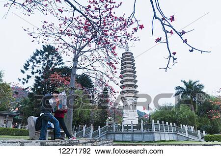 Stock Image - Two tourists checking their map in the garden of Nan Pu Tuo buddhist temple; Xiamen, Fujian Province, China. Fotosearch