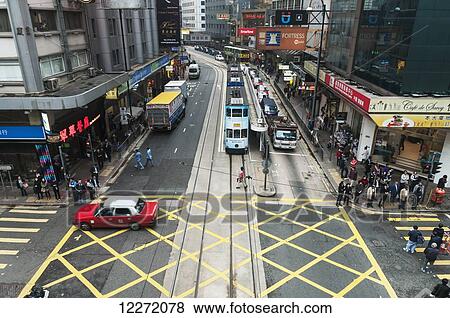 Stock Photo - Typical urban landscape on Hong Kong Island with pedestrians, crosswalk, red taxi and tram; Hong Kong, China. Fotosearch