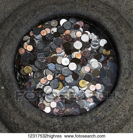 Stock Photograph - Various coins piled in a round receptacle; Seoul, South Korea. Fotosearch